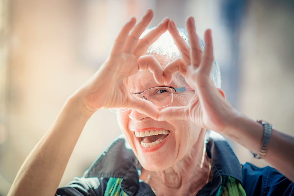 A senior woman making a heart shape with her hands