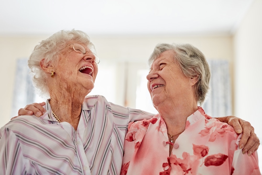 Two senior women laugh and smile at the best Concord assisted senior living community